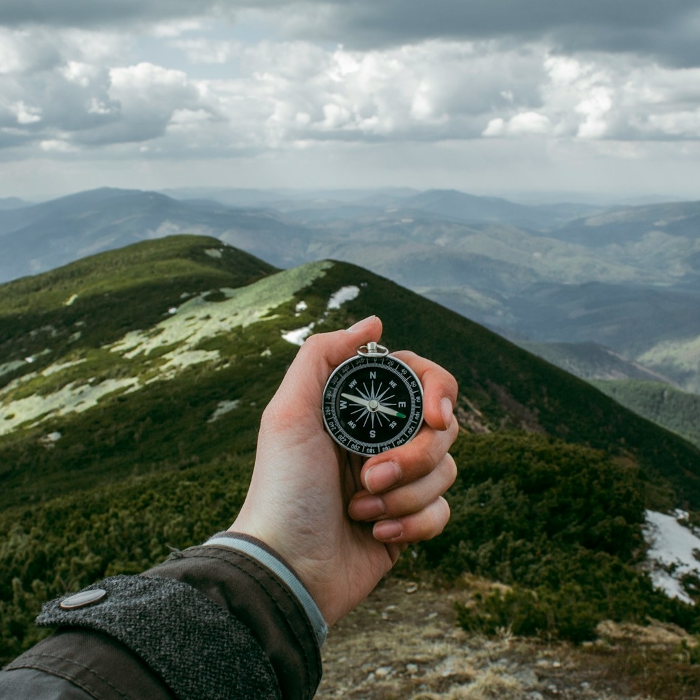 person holding silver compass